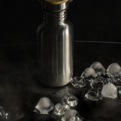 A stylish reusable water bottle next to a rolled-up towel.